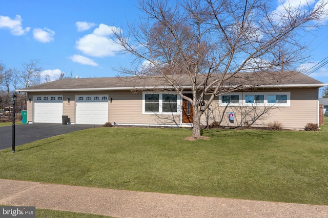 ranch-style home featuring aphalt driveway, an attached garage, and a front lawn