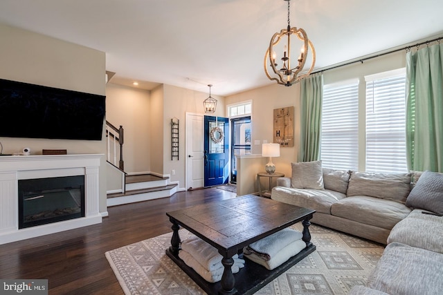 living area with stairway, wood finished floors, a wealth of natural light, and a chandelier