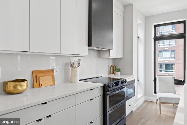 kitchen featuring light wood-style flooring, stainless steel electric stove, light countertops, white cabinets, and modern cabinets