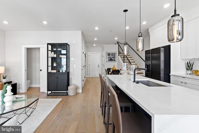 kitchen with recessed lighting, light wood-style flooring, black refrigerator with ice dispenser, white cabinetry, and modern cabinets