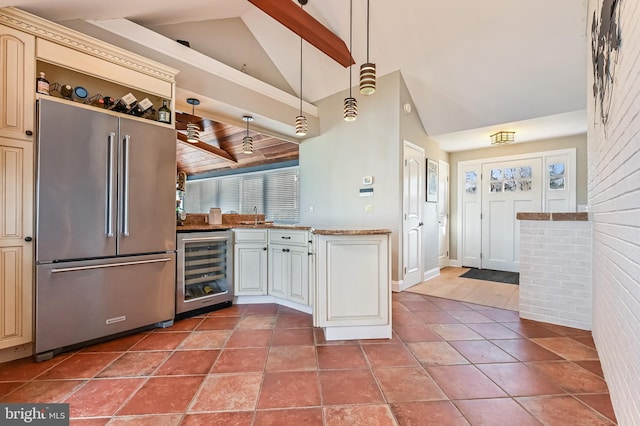 kitchen featuring high vaulted ceiling, beverage cooler, cream cabinets, brick wall, and high end refrigerator