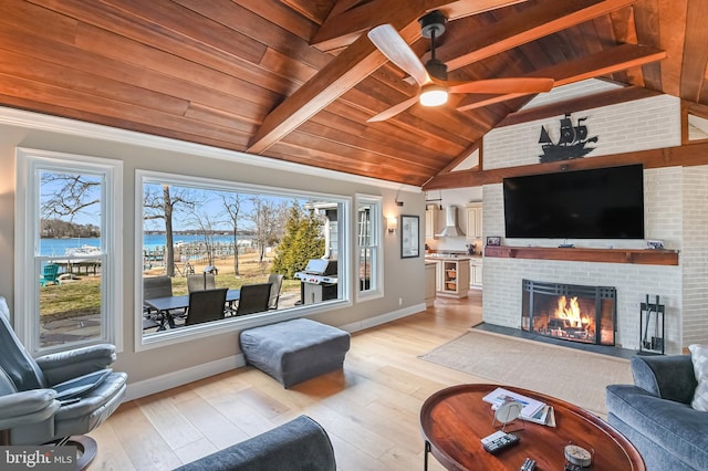 living room with wooden ceiling, light wood finished floors, baseboards, a brick fireplace, and vaulted ceiling with beams