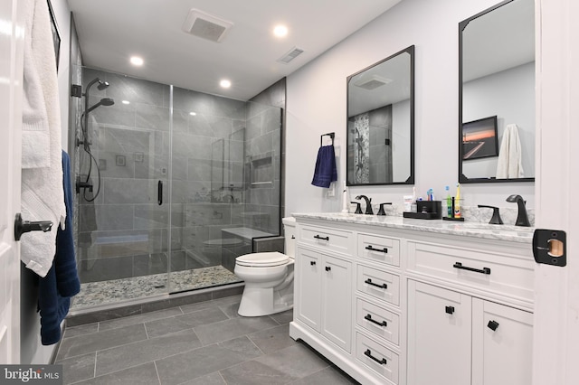 full bathroom featuring vanity, a shower stall, toilet, and visible vents