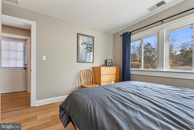 bedroom featuring light wood finished floors, visible vents, and baseboards