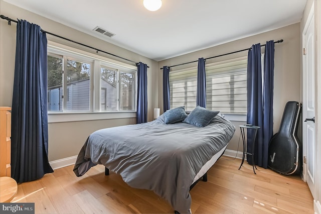 bedroom featuring visible vents, baseboards, and wood finished floors