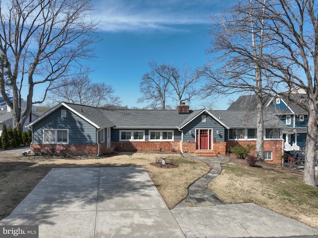 view of front facade featuring driveway, a front lawn, brick siding, and a chimney