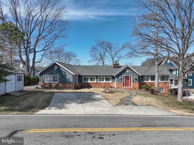 view of front of property with brick siding, a front lawn, a chimney, an outbuilding, and a storage unit