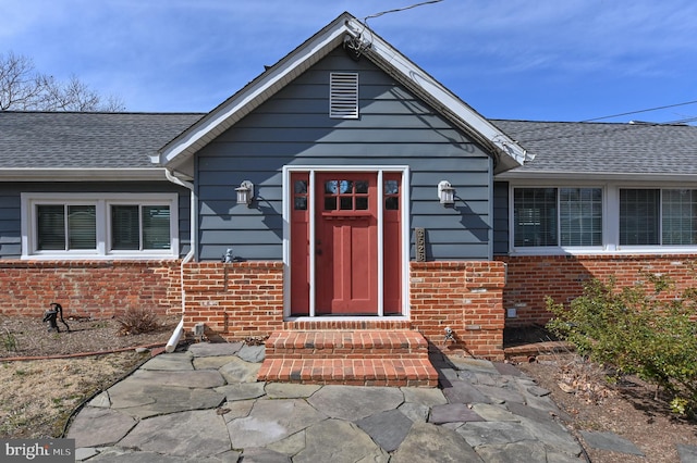 property entrance with brick siding and a shingled roof