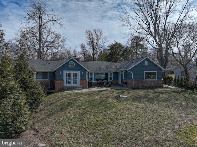 ranch-style home featuring brick siding, french doors, a chimney, and a front yard