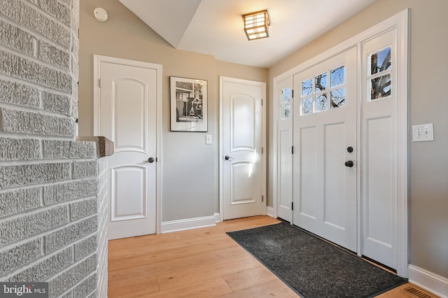 foyer entrance with stairway, visible vents, baseboards, and light wood finished floors