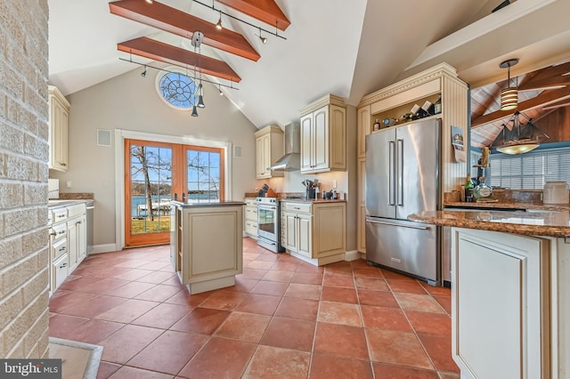 kitchen featuring light tile patterned floors, stainless steel appliances, cream cabinets, and wall chimney exhaust hood