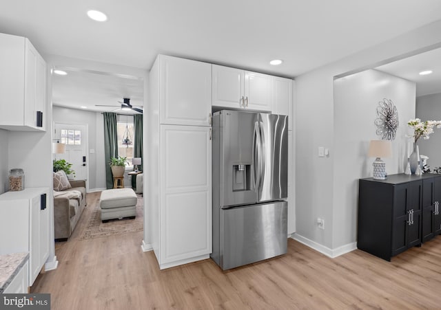 kitchen with light wood finished floors, stainless steel fridge, and white cabinetry