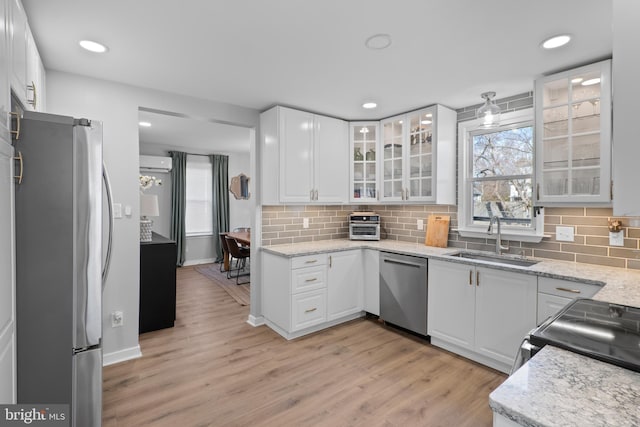 kitchen featuring white cabinetry, stainless steel appliances, light wood-type flooring, and a sink