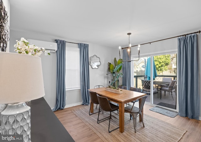 dining space featuring a chandelier, an AC wall unit, and light wood-style flooring