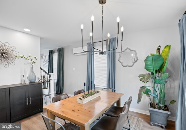 dining area with an inviting chandelier, an AC wall unit, baseboards, and light wood finished floors