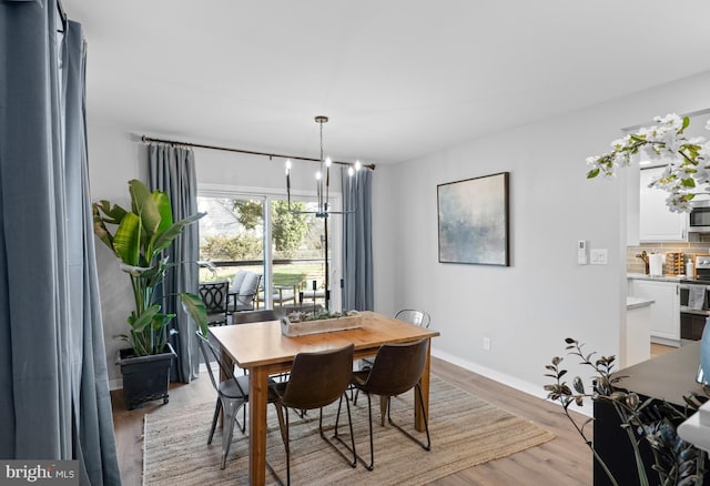 dining space featuring an inviting chandelier, light wood-style floors, and baseboards