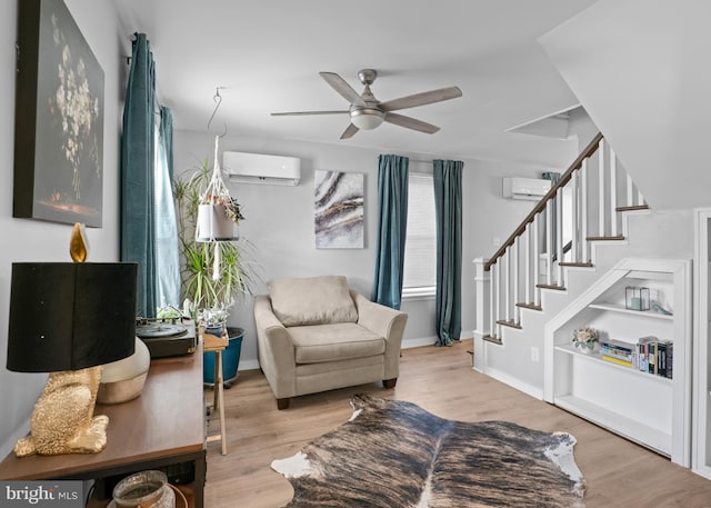 sitting room featuring a wall mounted air conditioner, wood finished floors, and stairs