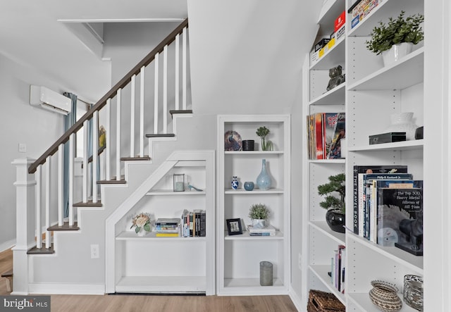 stairs featuring baseboards, wood finished floors, and a wall unit AC