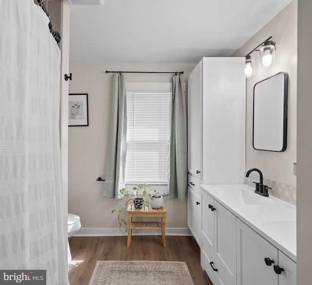 full bathroom with vanity, toilet, wood finished floors, and baseboards