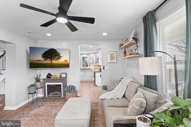 living room featuring a healthy amount of sunlight, a fireplace, baseboards, and wood finished floors