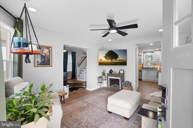 living room with stairway, a ceiling fan, wood finished floors, recessed lighting, and a fireplace