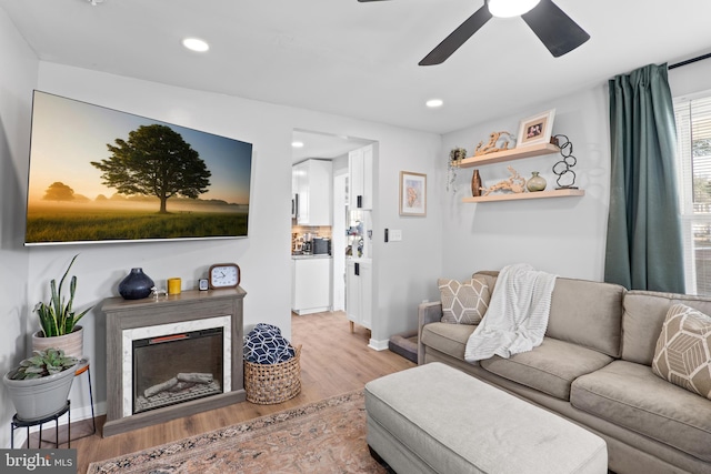 living area with recessed lighting, a premium fireplace, and wood finished floors