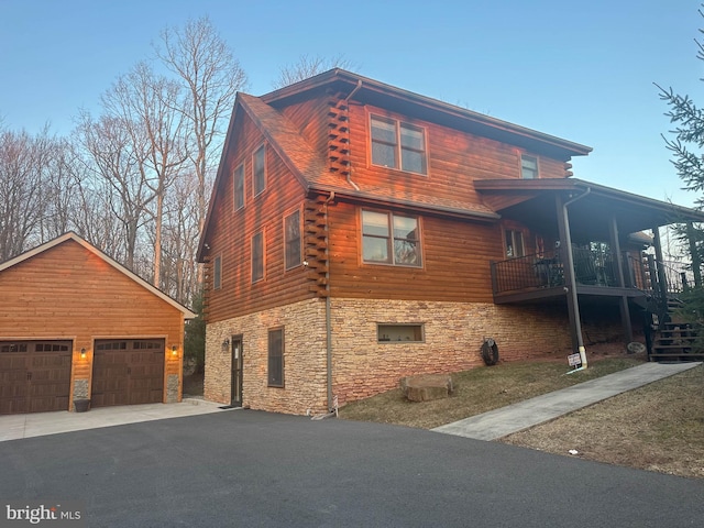 view of home's exterior featuring log siding, stone siding, an outbuilding, and a detached garage