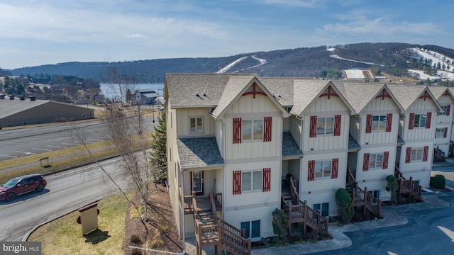 view of front facade featuring a mountain view, board and batten siding, roof with shingles, and stairs