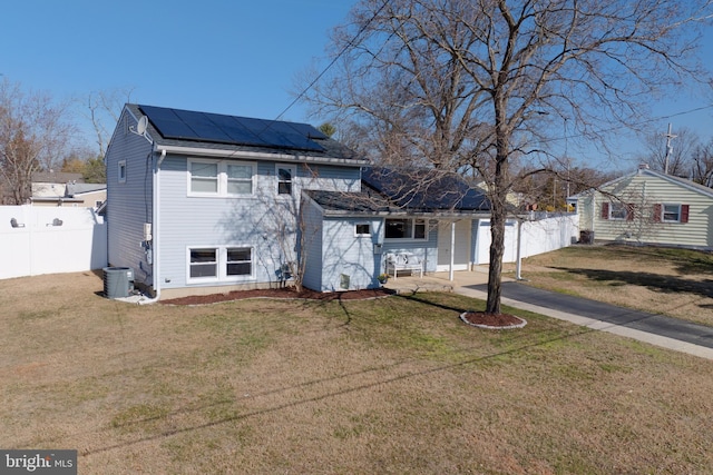 view of front facade featuring solar panels, fence, a front yard, central AC, and driveway