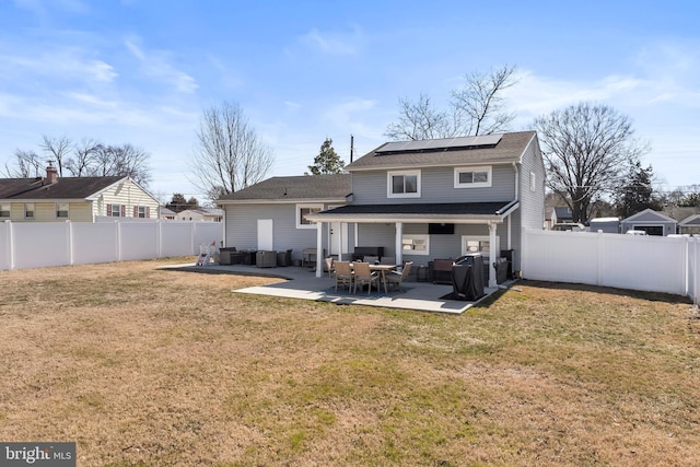 back of property featuring a yard, a patio, solar panels, and a fenced backyard