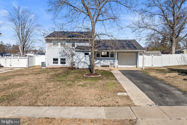 view of front of house with roof mounted solar panels, fence, a front lawn, and a gate