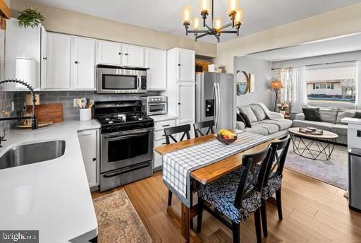 kitchen featuring light wood-type flooring, a sink, stainless steel appliances, white cabinets, and light countertops