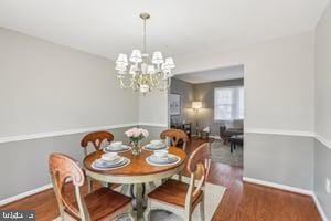 dining space featuring wood finished floors, baseboards, and a chandelier