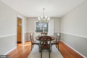 dining area featuring a chandelier, baseboards, and wood finished floors