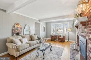 living room with beamed ceiling, washer / clothes dryer, wood finished floors, baseboards, and a brick fireplace