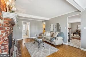 living room with a brick fireplace, wood finished floors, beamed ceiling, and baseboards