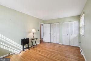 bedroom featuring baseboards, two closets, and wood finished floors