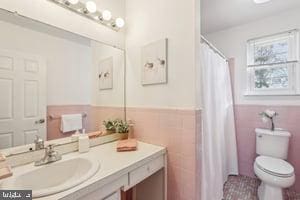 full bath with vanity, tile walls, toilet, and wainscoting