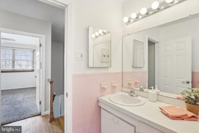 bathroom featuring wainscoting, tile walls, vanity, and wood finished floors