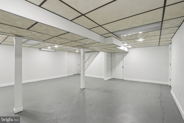 finished basement featuring a drop ceiling and baseboards