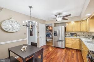 kitchen featuring dark wood finished floors, light brown cabinetry, light countertops, stainless steel refrigerator with ice dispenser, and ceiling fan with notable chandelier