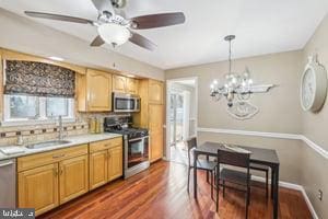 kitchen featuring a sink, backsplash, light countertops, stainless steel appliances, and dark wood-style flooring