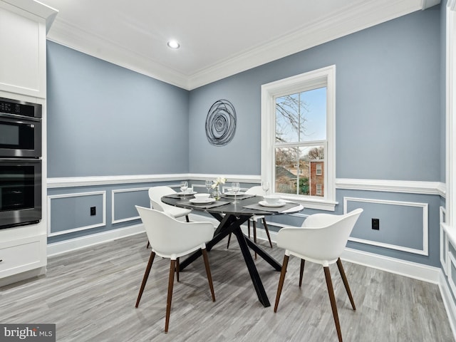 dining space with recessed lighting, light wood-type flooring, a wainscoted wall, and crown molding