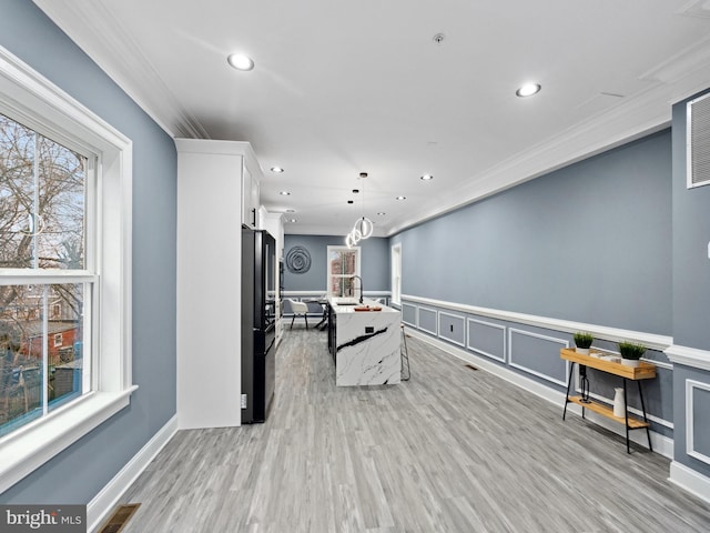 interior space featuring visible vents, recessed lighting, ornamental molding, wainscoting, and light wood-type flooring