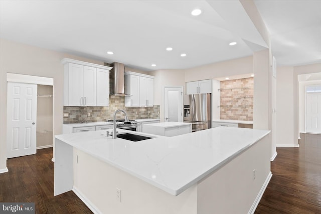 kitchen with a sink, a spacious island, stainless steel fridge with ice dispenser, wall chimney range hood, and decorative backsplash