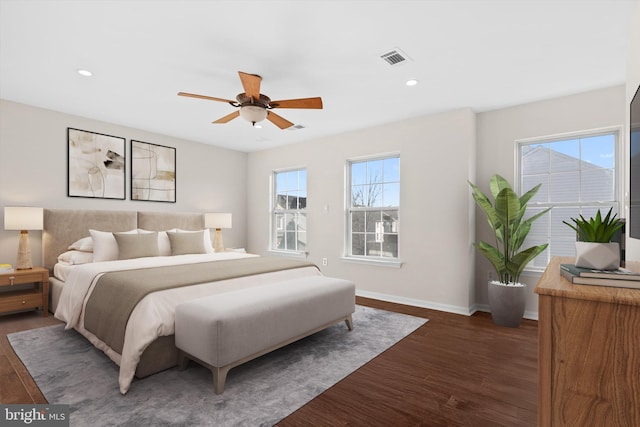 bedroom with dark wood finished floors, multiple windows, baseboards, and visible vents