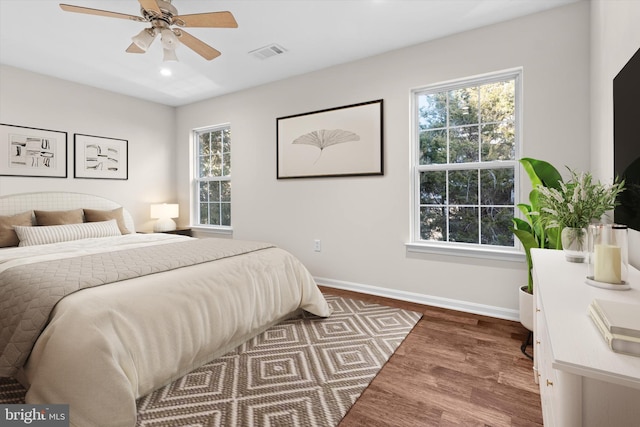 bedroom with dark wood finished floors, baseboards, visible vents, and ceiling fan