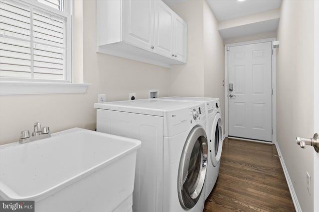 washroom with a sink, baseboards, washer and clothes dryer, cabinet space, and dark wood-style flooring