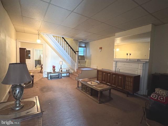 carpeted living room featuring stairway and a paneled ceiling