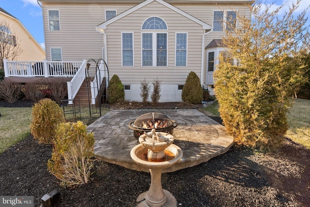 back of property with a wooden deck, a patio area, crawl space, and a fire pit